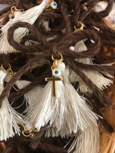 Load image into Gallery viewer, Brown Bow-tied rope with gold cross, ivory tassel, and white and turquoise mati. Comes with straight pin attached in the back. Sold in quantities of 10. #Martyrika